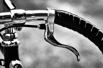 Black and white photograph of a classic bicycle. Bicycle handlebar with winding and brake.