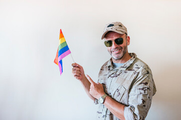 A handsome man in camouflage military uniform and a multicolored pride flag.