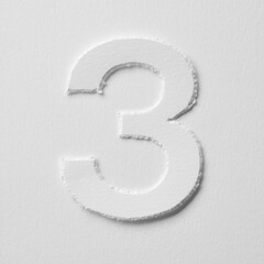 The number three is made of white paper on a white background.