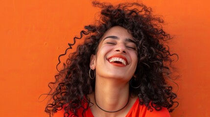Happy woman with curly hair on orange background, smiling