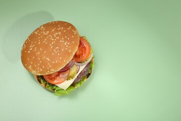 Burger with delicious patty on green background, top view. Space for text