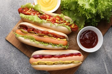 Delicious hot dogs with different toppings served on grey table, flat lay