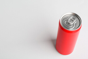 Energy drink in red can on light grey background, space for text