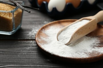 Pate and scoop with baking powder on black wooden table, closeup - obrazy, fototapety, plakaty