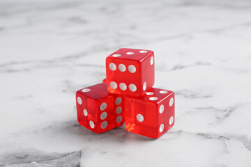 Three red game dices on white marble table, closeup