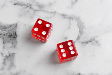 Two red game dices on white marble table, above view