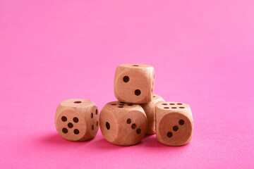 Many wooden game dices on pink background, closeup