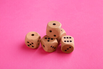 Many wooden game dices on pink background