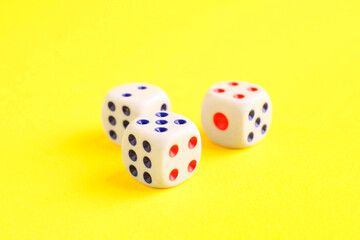 Three white game dices on yellow background, closeup