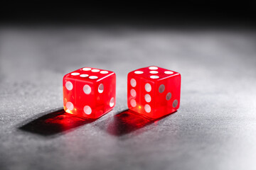 Two red game dices on grey textured table, closeup