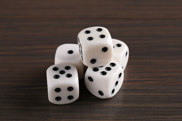Many white game dices on wooden table, closeup