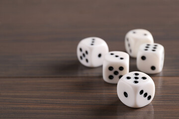 Many white game dices on wooden table, closeup. Space for text