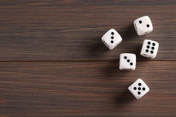 Many white game dices on wooden table, top view. Space for text