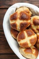 Hot cross buns in basket on wooden table, top view