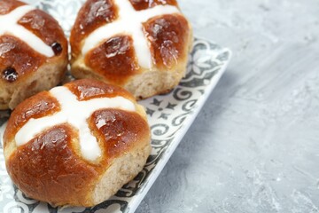 Tasty hot cross buns on gray textured table, closeup. Space for text