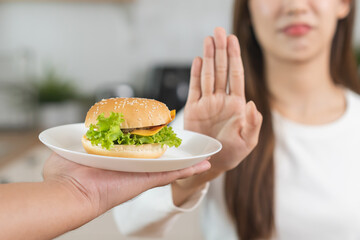 Diet, struggle asian young woman hand gesture reject to eat burger, push out or deny fast, junk...