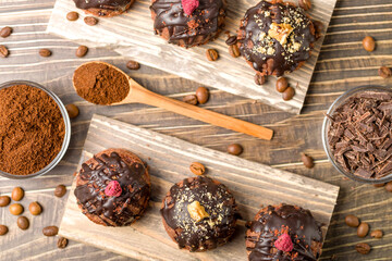 Round chocolate cakes. Decorated with candied raspberries. Wooden background.