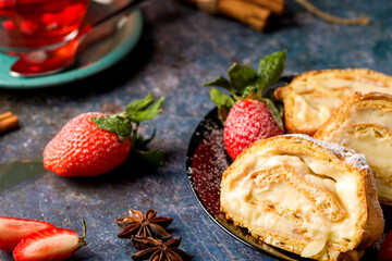 Sliced rolls with custard. The dessert is decorated with fresh strawberries.