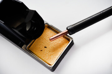 Soldering iron with a wooden handle in the holder. A soldering iron stand.