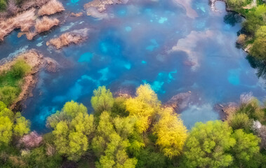 Fototapeta na wymiar View from the air of the turquoise Lake Balykty, in the spring among green hills, and a blooming orchard near the Shymkent region of Kazakhstan.