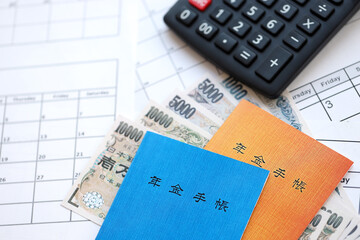 Japanese pension insurance booklets on table with yen money bills and calculator on table close up