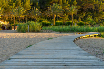 Curved wooden slated pathway at the beach leading to summer adventure and sundowners