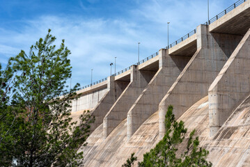 Side and bottom view of a dry concrete river dam with trees next to it