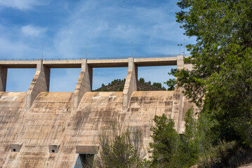 Front bottom view of a dry concrete river dam with trees next to it