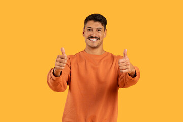 Smiling guy with thumbs up on orange backdrop