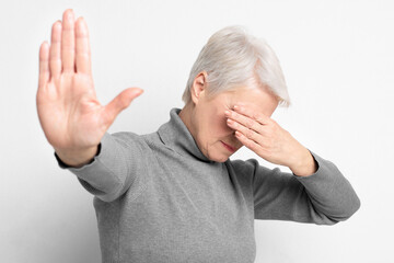 Elderly woman with hand up in refusal
