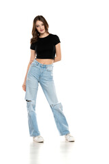 Young female model wearing ripped jeans and black shirt posing on a white background. Front view