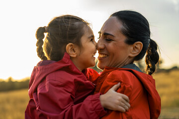 A mother and daughter exchange smiles full of love, encapsulated in the golden glow of sunset...