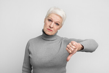 Senior woman giving thumbs down with displeasure