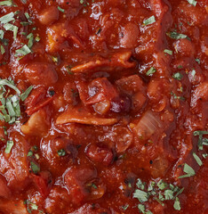 Southern baked beans with bacon strips and garnished with herbs.