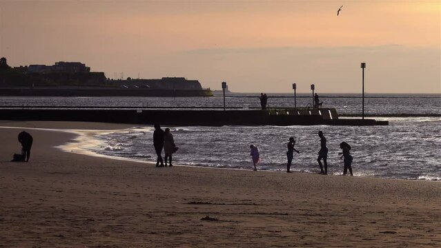 family playing on the beach at sunset