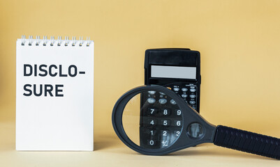 The word DISCLOSURE writing in a notepad. Magnifying glass and calculator on a yellow background