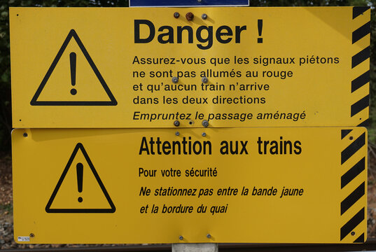 Safety is important on Europe’s busy train systems. Danger signs at a rural train station in France caution pedestrians to follow signals, look both directions, stand away from the yellow line.