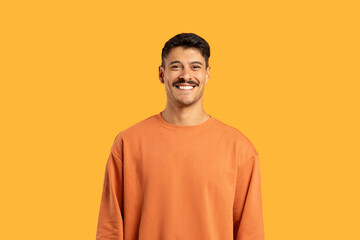 Smiling millennial in orange smiling at camera