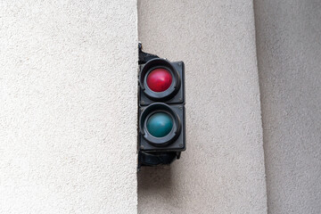 Double red and green traffic light hangs on a white concrete wall in front of the entrance to an...