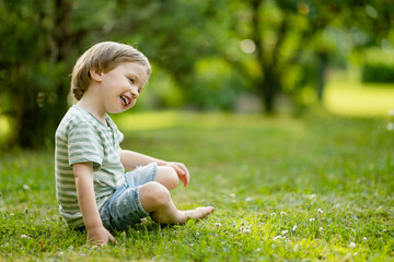 Adorable little boy having fun outdoors on sunny summer day. Kid running outdoors. Child exploring nature. Summer activities for kids.
