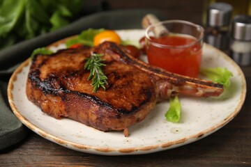 Tasty grilled meat, rosemary and marinade on wooden table, closeup