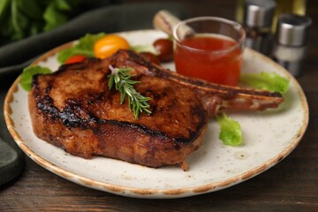 Tasty grilled meat, rosemary and marinade on wooden table, closeup