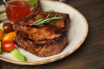 Tasty marinated meat, rosemary and tomatoes on wooden table, closeup