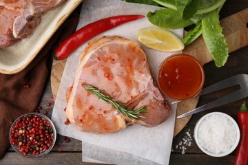 Flat lay composition with raw marinated meat, lemon, rosemary and spices on wooden table