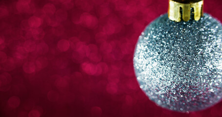 Christmas bauble. Festive background. Winter holiday. Silver metallic glitter texture ball on blur red magenta color bokeh lights abstract art with empty space.