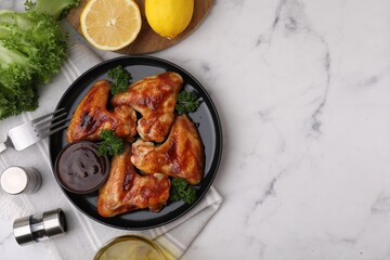Flat lay composition with marinade and chicken wings on white marble table. Space for text