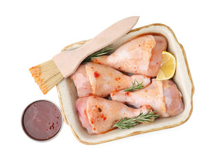 Fresh marinade, basting brush, raw chicken drumsticks, rosemary and lemon isolated on white, top view
