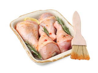 Raw marinated chicken drumsticks with rosemary, lemon and basting brush isolated on white