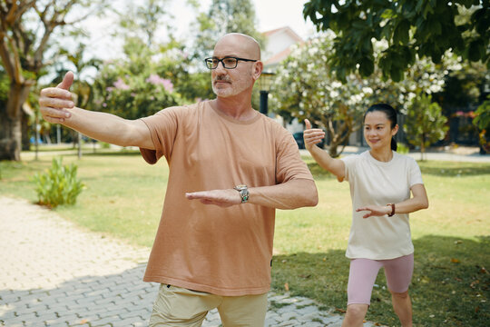 Mature diverse couple practicing tai chi in city park - Powered by Adobe