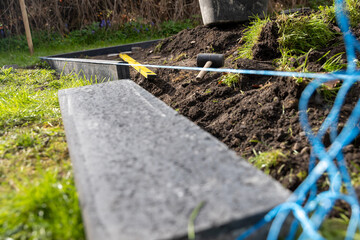 Eine Fläche im Garten vermessen um Bordsteine zu setzen